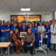 Grupo de profesionales de la salud y staff posando juntos cerca de equipo ECMO en una sala de hospital.