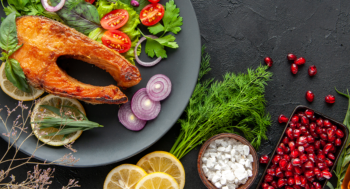 Plato con salmón, verduras frescas y hierbas, representando una dieta antiinflamatoria para la salud y el bienestar