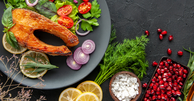 Plato con salmón, verduras frescas y hierbas, representando una dieta antiinflamatoria para la salud y el bienestar
