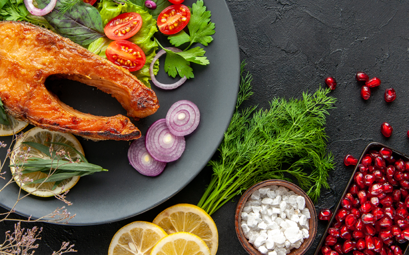 Plato con salmón, verduras frescas y hierbas, representando una dieta antiinflamatoria para la salud y el bienestar