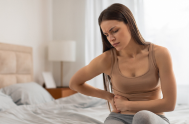 Mujer sosteniendo la parte baja del abdomen por dolor, representando causas comunes de malestar abdominal o cólicos.