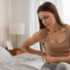 Mujer sosteniendo la parte baja del abdomen por dolor, representando causas comunes de malestar abdominal o cólicos.