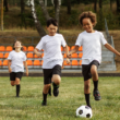 Tres niños jugando fútbol en un campo lleno de paso, representando buena salud física.