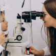 Una oculista examina los ojos de una niña pequeña, durante un examen de la vista.