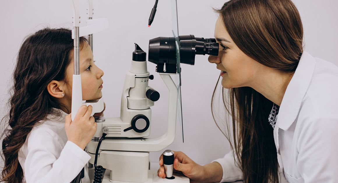 Una oculista examina los ojos de una niña pequeña, durante un examen de la vista.