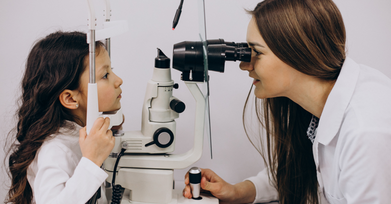 Una oculista examina los ojos de una niña pequeña, durante un examen de la vista.
