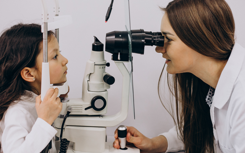 Una oculista examina los ojos de una niña pequeña, durante un examen de la vista.