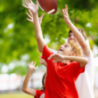 Escena energética de niños jugando a atrapar un balón de fútbol, rodeados de árboles en un parque.