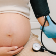 Healthcare provider measures a pregnant person's blood pressure during a prenatal checkup.
