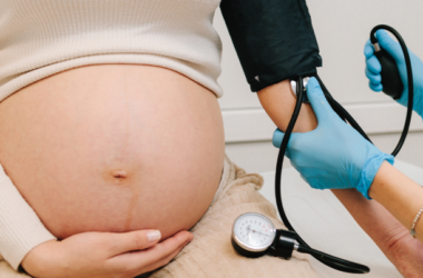 Healthcare provider measures a pregnant person's blood pressure during a prenatal checkup.