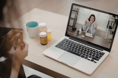 Un paciente enfermo teniendo una videollamada con un profesional de la salud desde una computadora.