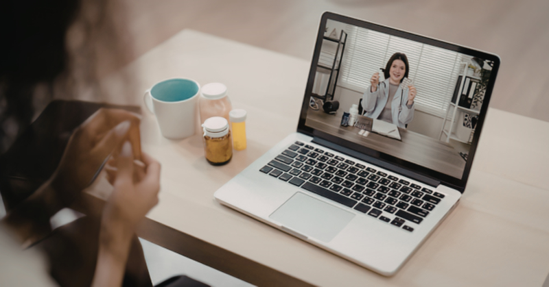 Un paciente enfermo teniendo una videollamada con un profesional de la salud desde una computadora.