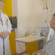 El Dr. Philip E. Fiddler, Director del UMC Burn Center, habla con Javier Diaz, un paciente sentado en la cama de un hospital. La habitación está llena de equipo médico.