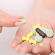 Una mano sostiene varias pastillas: tabletas verdes, píldoras amarillas y una cápsula negra. Otra mano sostiene una tableta verde, representando el uso seguro de antibióticos.