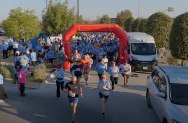 Personas corriendo a través de un arco durante una carrera comunitaria de 5 km.