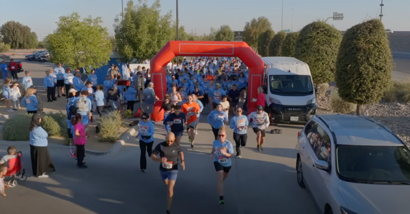 Personas corriendo a través de un arco durante una carrera comunitaria de 5 km.