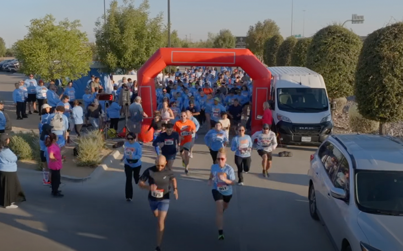 Personas corriendo a través de un arco durante una carrera comunitaria de 5 km.