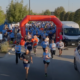 Personas corriendo a través de un arco durante una carrera comunitaria de 5 km.